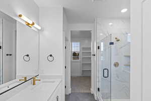 Full bathroom with vanity, a marble finish shower, and a walk in closet