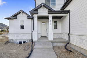 View of exterior entry with stone siding, a porch, and a mountain view