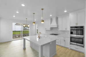 Kitchen featuring backsplash, light stone counters, white cabinetry, stainless steel appliances, and recessed lighting
