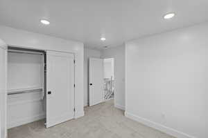 Bedroom 4 featuring light colored carpet, recessed lighting, and a closet