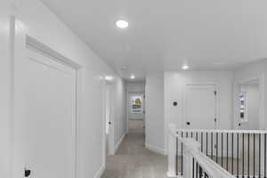 Hall featuring light colored carpet, recessed lighting, and an upstairs landing
