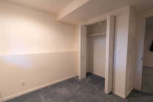 Unfurnished bedroom with dark colored carpet and a closet