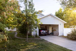 View of side of home featuring concrete driveway, a yard, a chimney, and a garage