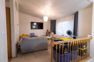 Carpeted living area with a chandelier and vaulted ceiling