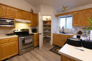 Kitchen featuring stainless steel appliances, light countertops, and brown cabinets