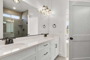 Bathroom featuring a stall shower, double vanity, and light tile patterned flooring