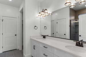 Bathroom featuring double vanity, a shower stall, light tile patterned floors, a chandelier, and recessed lighting