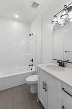 Bathroom with washtub / shower combination, dark tile patterned floors, and vanity