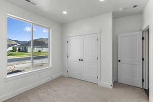 Unfurnished bedroom featuring light colored carpet, a mountain view, a closet, recessed lighting, and a residential view