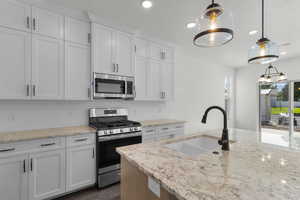 Kitchen with appliances with stainless steel finishes, recessed lighting, white cabinetry, decorative backsplash, and decorative light fixtures