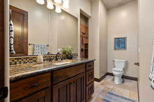 Full bath featuring vanity, stone tile flooring, and a tile shower
