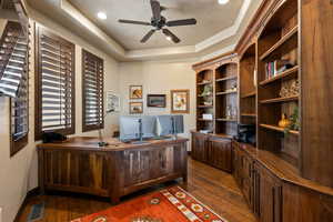 Office space with a tray ceiling, a ceiling fan, dark wood finished floors, and recessed lighting