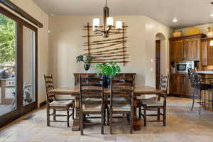 Dining area with stone tile flooring, a chandelier, and arched walkways