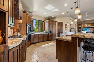 Kitchen featuring a skylight, decorative light fixtures, stainless steel appliances, recessed lighting, and stone tile floors