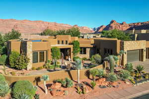 Pueblo-style house featuring a mountain view, stucco siding, a patio, and a garage