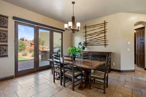 Dining room featuring arched walkways, a chandelier, and stone tile flooring