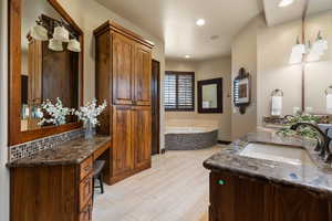Full bathroom featuring a garden tub, double vanity, and recessed lighting