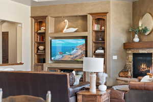 Living area featuring built in shelves and a stone fireplace