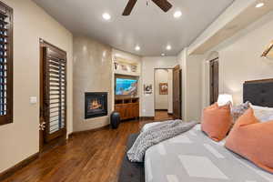 Bedroom with dark wood finished floors, recessed lighting, a large fireplace, and ceiling fan