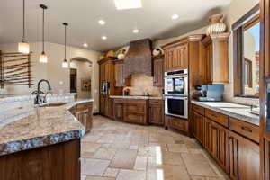 Kitchen with stainless steel appliances, decorative light fixtures, recessed lighting, backsplash, and arched walkways