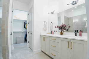 Bathroom with a spacious closet, double vanity, light tile patterned flooring, and a walk in shower