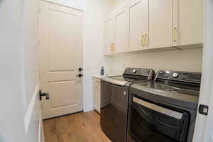 Laundry area with dark wood-style floors, washing machine and dryer, and cabinet space