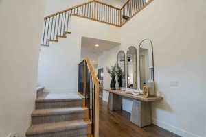 Staircase with wood finished floors and a towering ceiling
