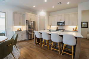 Kitchen with appliances with stainless steel finishes, tasteful backsplash, dark wood-style floors, a kitchen breakfast bar, and recessed lighting