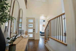 Foyer with dark wood-style floors, stairs, a towering ceiling, and a ceiling fan