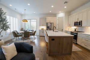 Kitchen featuring tasteful backsplash, stainless steel appliances, recessed lighting, dark wood finished floors, and a kitchen island with sink