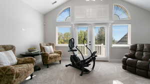 Upstairs living space  with light colored carpet, french doors to balcony and high vaulted ceiling