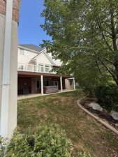 Back of property with a patio area, brick siding, a hot tub, and a yard