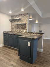 Kitchen featuring a peninsula, dark wood finished floors, tasteful backsplash, and a textured ceiling