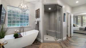 Bathroom featuring a freestanding soaking bath, TV hookup, a shower stall, connected bathroom, a chandelier, and parquet floors