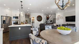Dining space featuring dark wood-type flooring, recessed lighting, stairway, and a chandelier