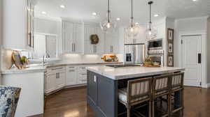 Gorgeous Kitchen featuring quartz countertops, oversized island with outlets and built in gas range,  ornamental molding, a kitchen breakfast bar, appliances with stainless steel finishes.