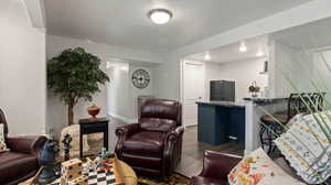 Living room featuring dark wood-type flooring and a textured ceiling- cozy sitting area next to wet bar and drinking fountain for sports court access.