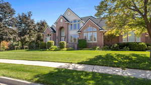 Welcoming exterior showcasing new roof, large windows, elegant entry and green lawn with mature trees.