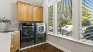 Gorgeous large laundry room with vaulted ceiling, large windows, sink and tons of storage and counter space, Washroom with dark wood-style floors, separate washer and dryer.