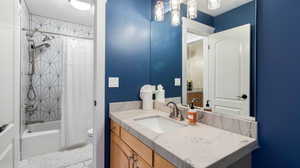 Full bathroom with Jack and Jill shower / bath combo, a textured ceiling, vanity, light tile patterned floors, and a chandelier