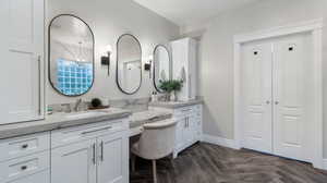 Bathroom featuring two vanities, a chandelier, and dual walk-in closets