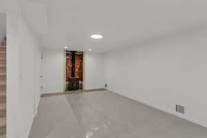 Basement family room featuring a wood stove, new carpet, and recessed lighting