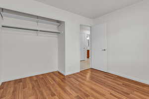 Unfurnished bedroom featuring wood finished floors, closet space and baseboards