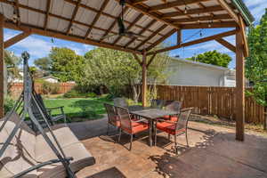 Fenced backyard featuring ceiling fan, outdoor dining space, and a patio
