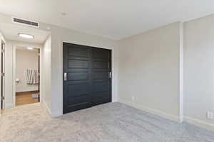 Unfurnished bedroom featuring light colored carpet and a closet