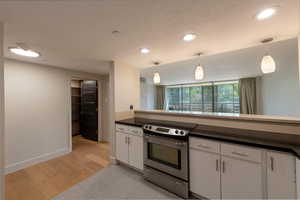 Kitchen featuring stainless steel electric range, pendant lighting, white cabinetry, light tile patterned floors, and recessed lighting