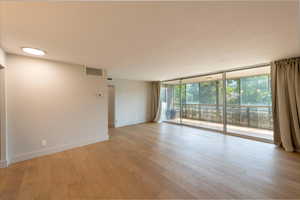 Unfurnished room featuring floor to ceiling windows and light wood-style flooring