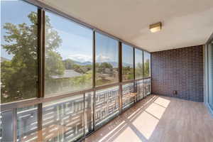 Unfurnished sunroom featuring brick wall, wood finished floors, a mountain view, and expansive windows