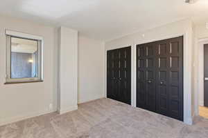 Unfurnished bedroom with two closets and carpet flooring