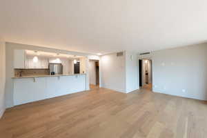 Unfurnished living room featuring baseboards and light wood-style floors